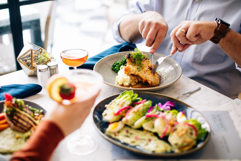 Colorful cocktails and dinner plates on a white marble table.